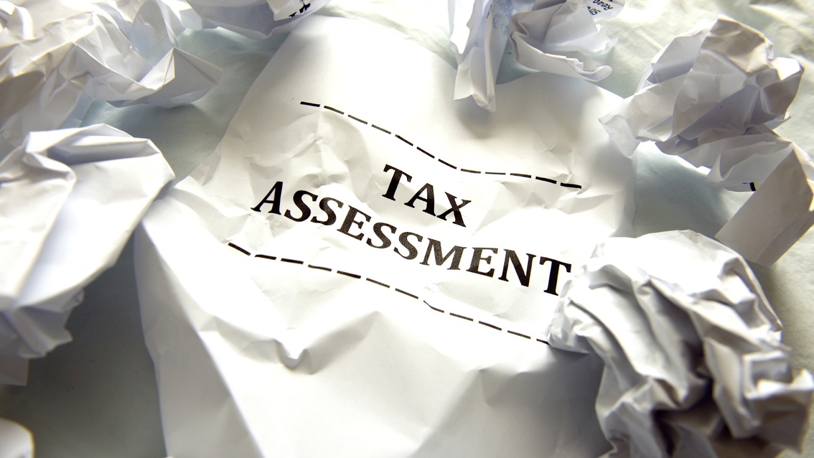 Tax assessment with crumpled papers around it