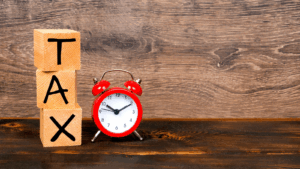 Wooden blocks and alarm clock representing tax deadline