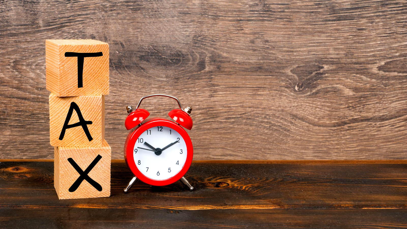 Wooden blocks and alarm clock representing tax deadline