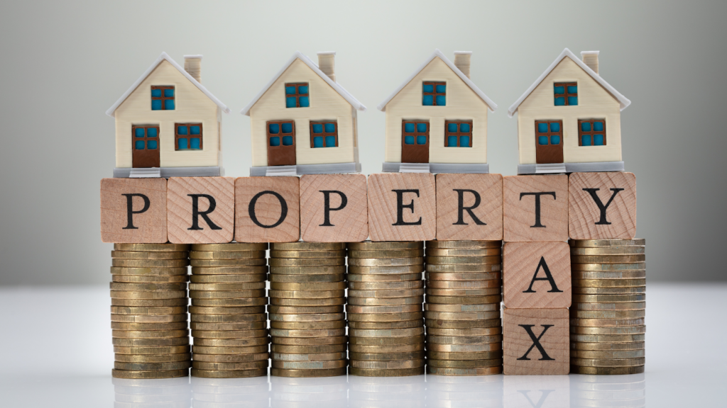 Property Tax Concept With Stack Of Coins And House Models