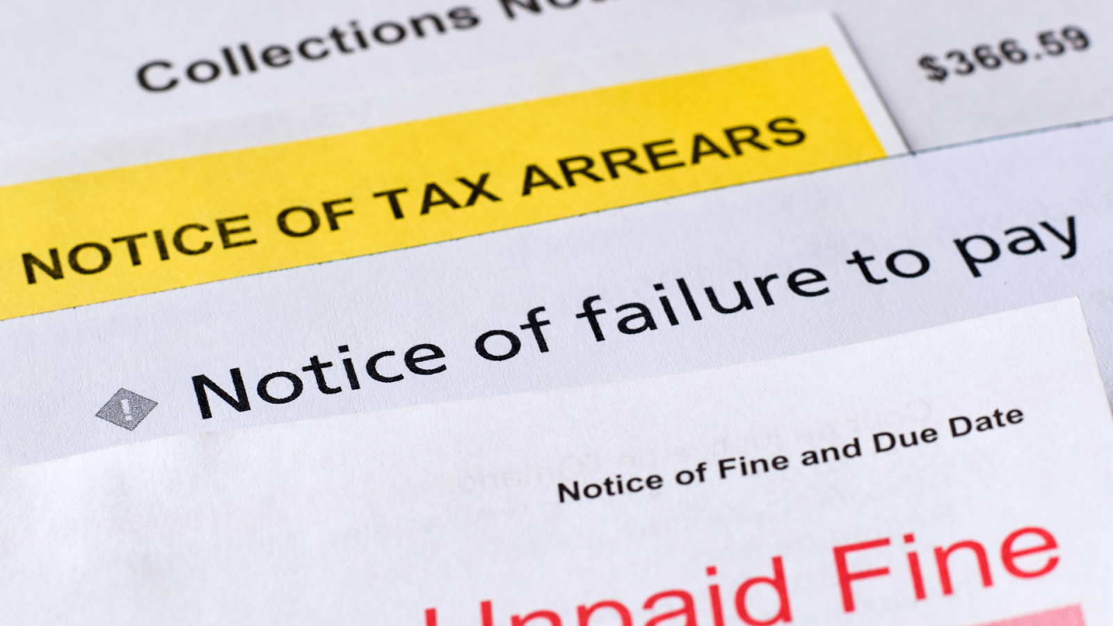 A stack of delinquent property tax notices and unpaid fine documents