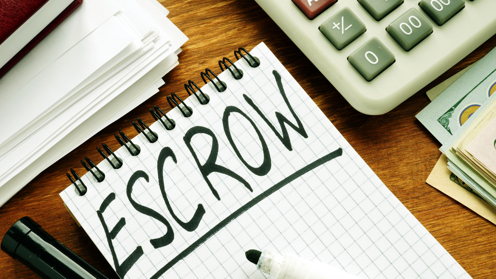 Escrow written on notepad with calculator and money on a desk