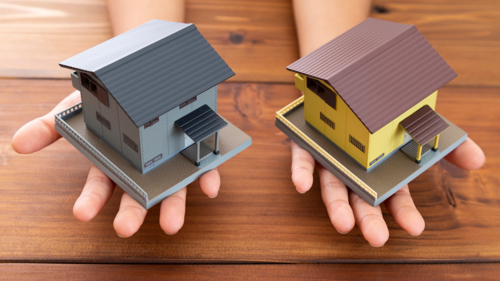 Hands holding two home models representing comparable property evidence preparation
